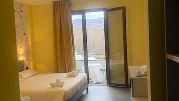 Habitación de hotel con dos camas, un escritorio y vistas al exterior.