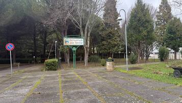 A paved area with a no parking sign, a welcome sign, and a trash bin.