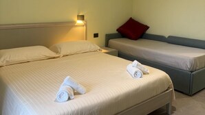 Une chambre d’hôtel avec un grand lit, un petit canapé et une table de chevet avec une lampe.
