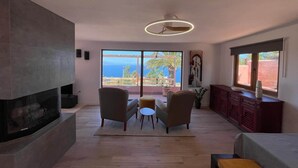 Een moderne woonkamer met een open haard, een eetgedeelte en uitzicht op de oceaan.