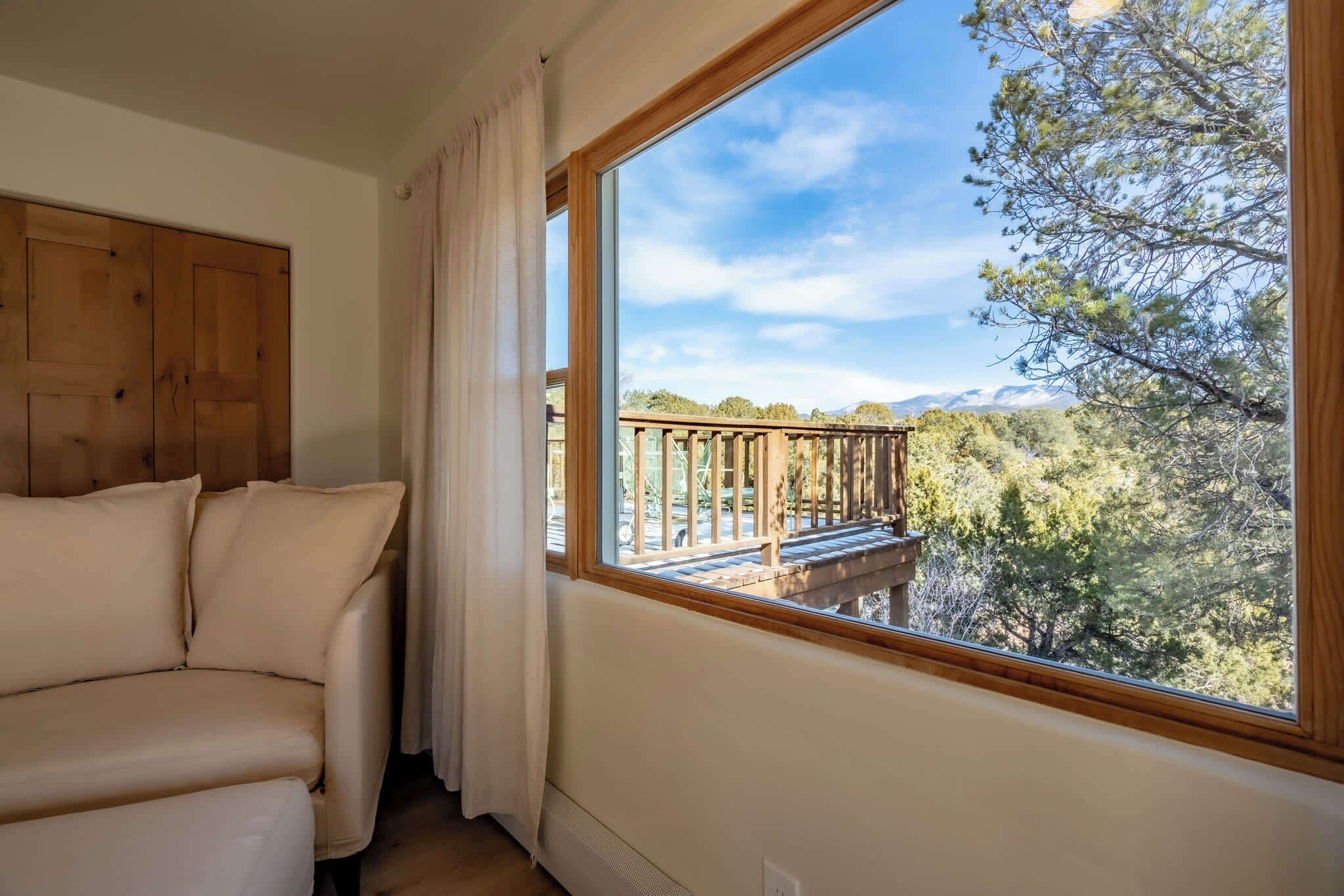 A room with a large window, a wooden door, and a beige sofa.