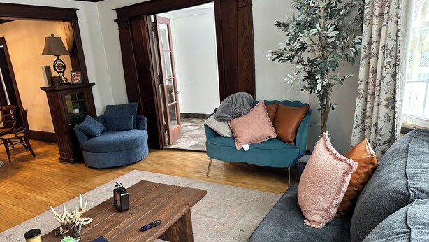 A living room with a wooden coffee table, two sofas, a blue armchair, and a large potted plant.
