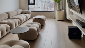 A modern living room with a large window, a sofa set, a coffee table, a TV, and a potted plant. - Adagio apartments by Nomad-In (Quito)