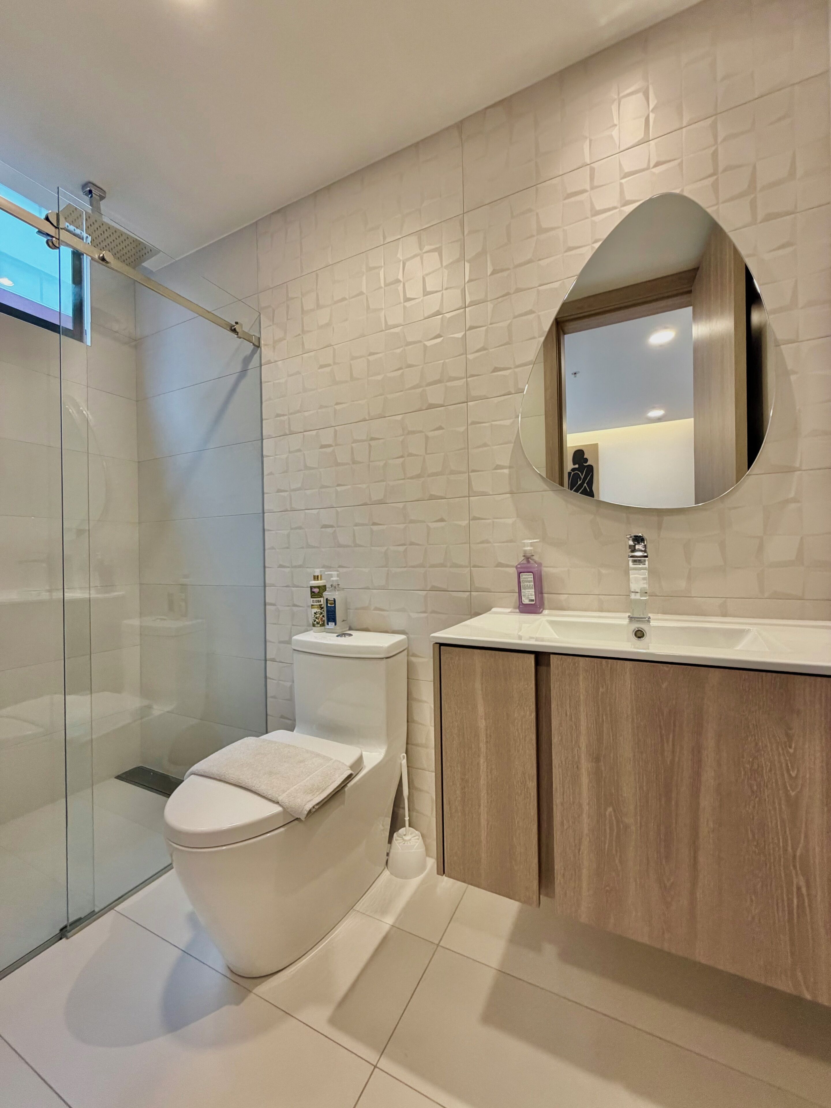 Un bagno moderno con cabina doccia in vetro, un water, un lavabo con specchio e un lavandino.