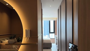 A modern hotel room with a curved wall, a built-in desk, a large window, and a wall-mounted TV. - Adagio apartments by Nomad-In (Quito)