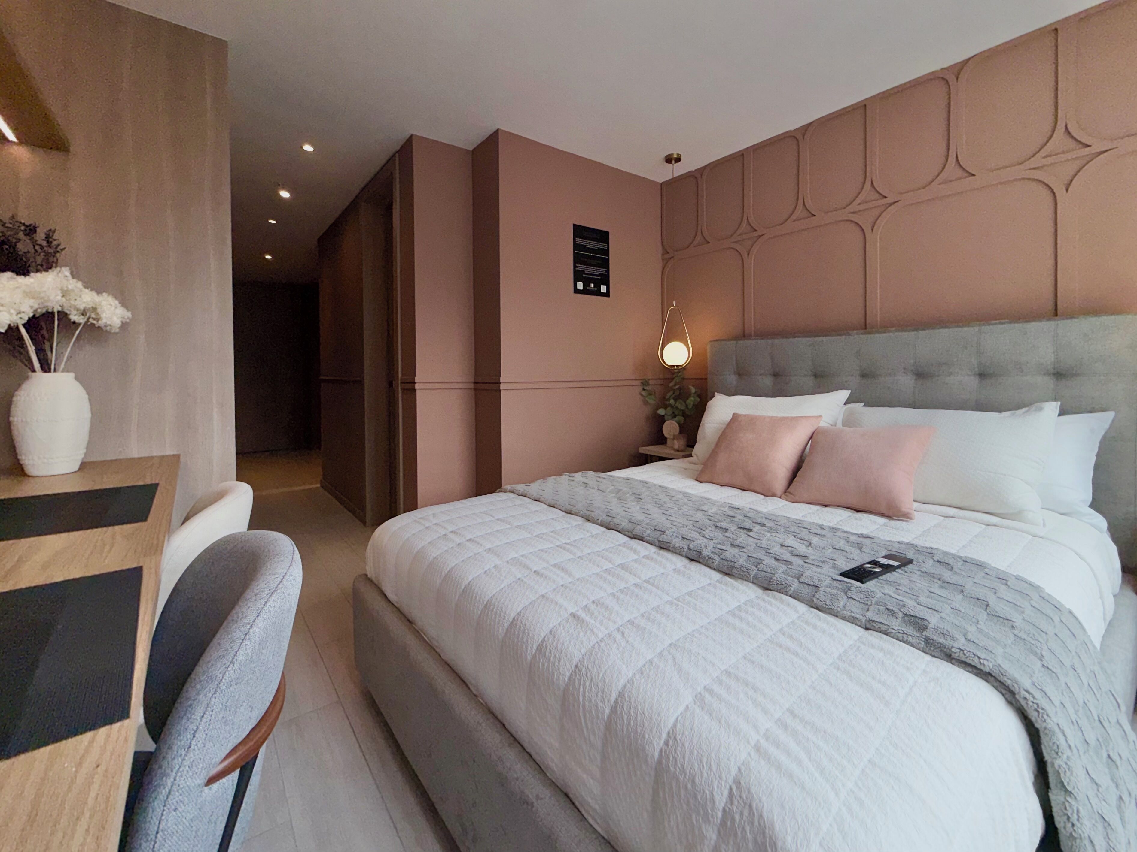 A modern bedroom with a large bed, a desk, and a chair.