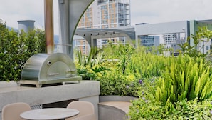 An outdoor patio with a grill, seating, and lush greenery. - Adagio apartments by Nomad-In (Quito)