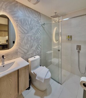 Une salle de bain moderne avec une douche à parois de verre, un miroir rond et un lavabo blanc.
