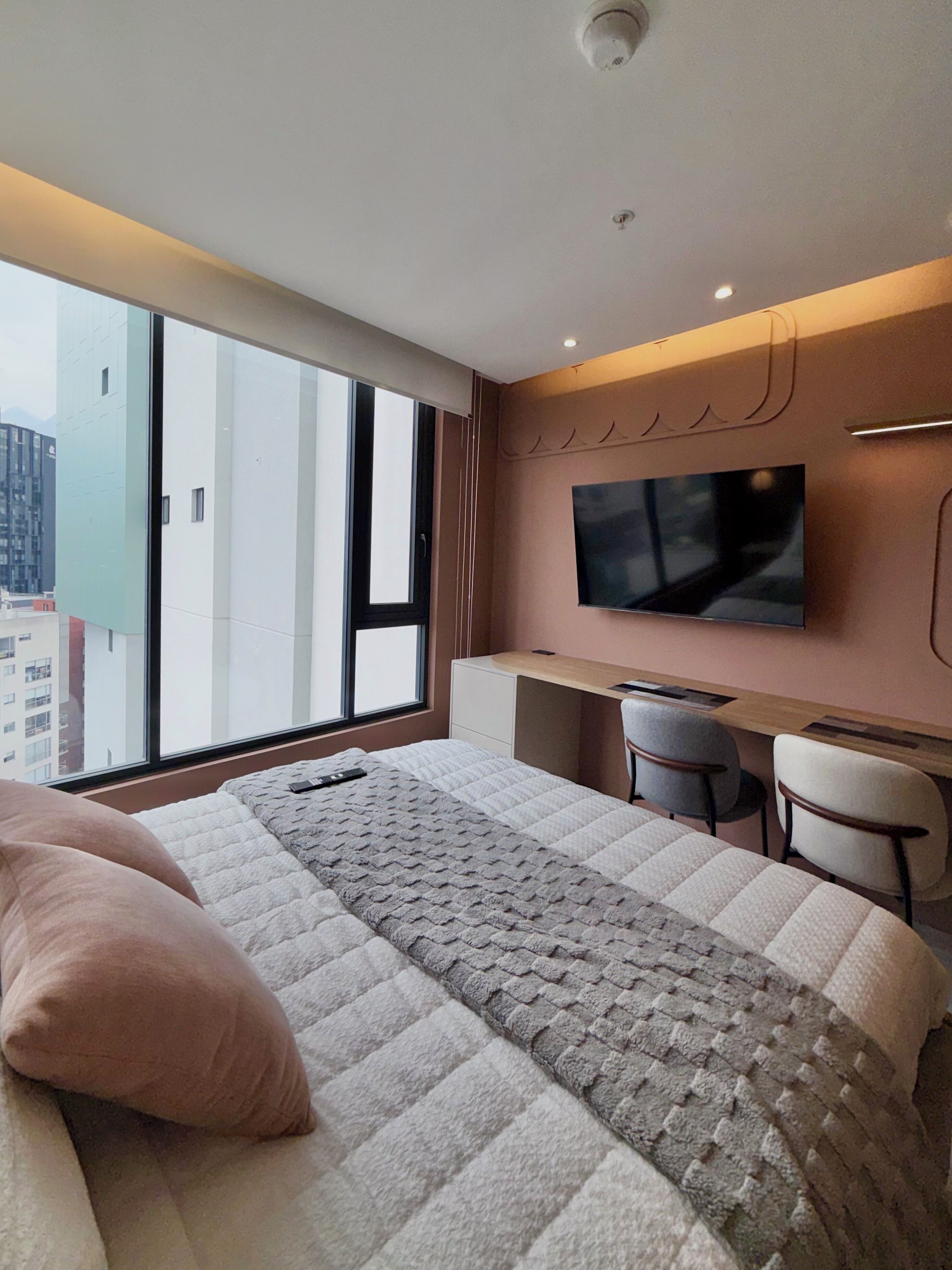 A modern hotel room with a large bed, a desk, and a TV.