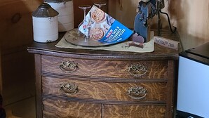 Een houten dressoir met een lamp, een pizzadoos en een teddybeer.