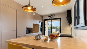 Een moderne keuken met een houten eiland, hangende lampen en uitzicht naar buiten.