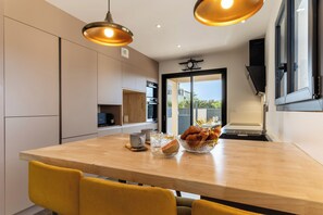 A modern kitchen with a wooden island, pendant lighting, and a view to the outside. - Villa Azura family villa jet pool near beach (Sérignan)