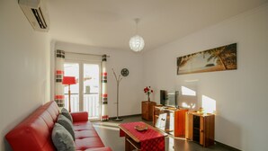 A living room with a red sofa, a wooden coffee table, a TV, and a painting on the wall. - FLH Vila Real Santo António Colourful Apartment (Vila Real de Santo António)
