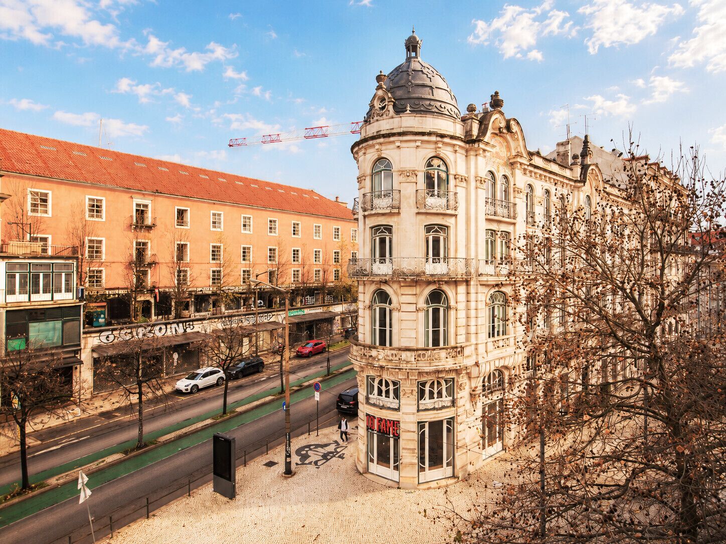 A historic building with a dome, a street with cars, and a pedestrian walkway.