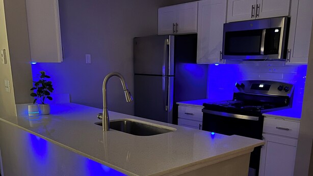 A modern kitchen with a central island, stainless steel appliances, and under-cabinet lighting. - 2 Bedroom 4 Min to Universal + Free Parking + Fast WiFi (Orlando)