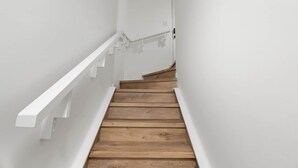 A narrow staircase with white railings and wooden steps.