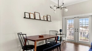 A dining area with a wooden table, black chairs, a black bench, and a chandelier.