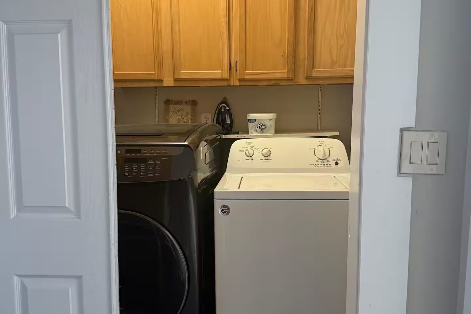 A compact laundry area with a washing machine, dryer, and a small cabinet above the machines.