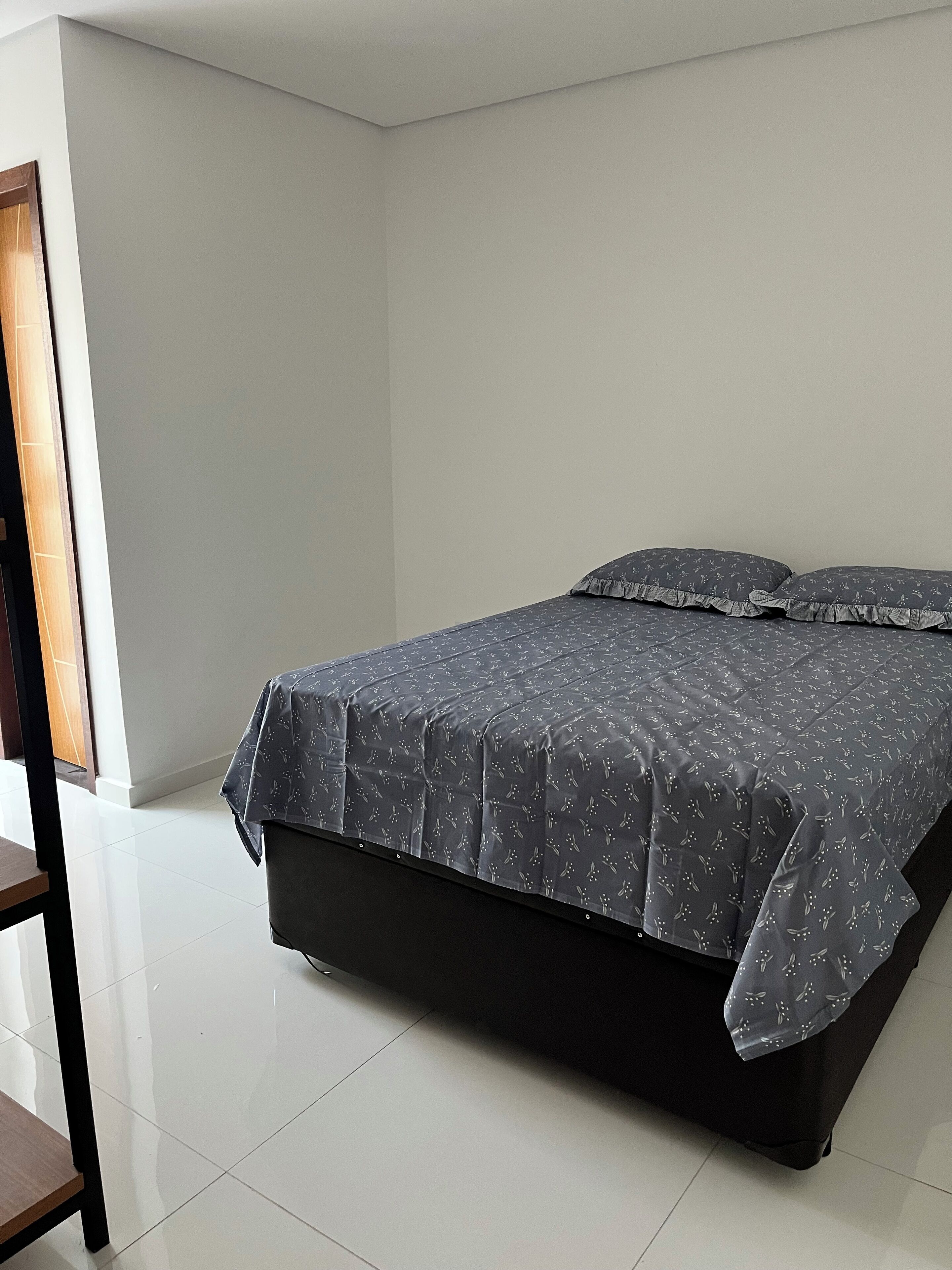 Un dormitorio con cama, una silla y una puerta.