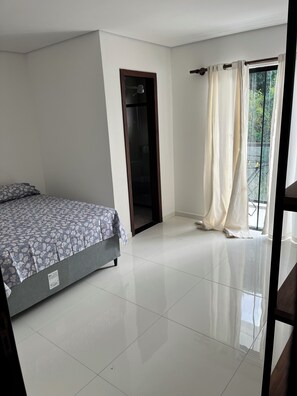 A bedroom with a bed, a door, a window with curtains, and a balcony. - Apartment 13, a 6-minute walk from Taperapuan beach. (Porto Seguro)