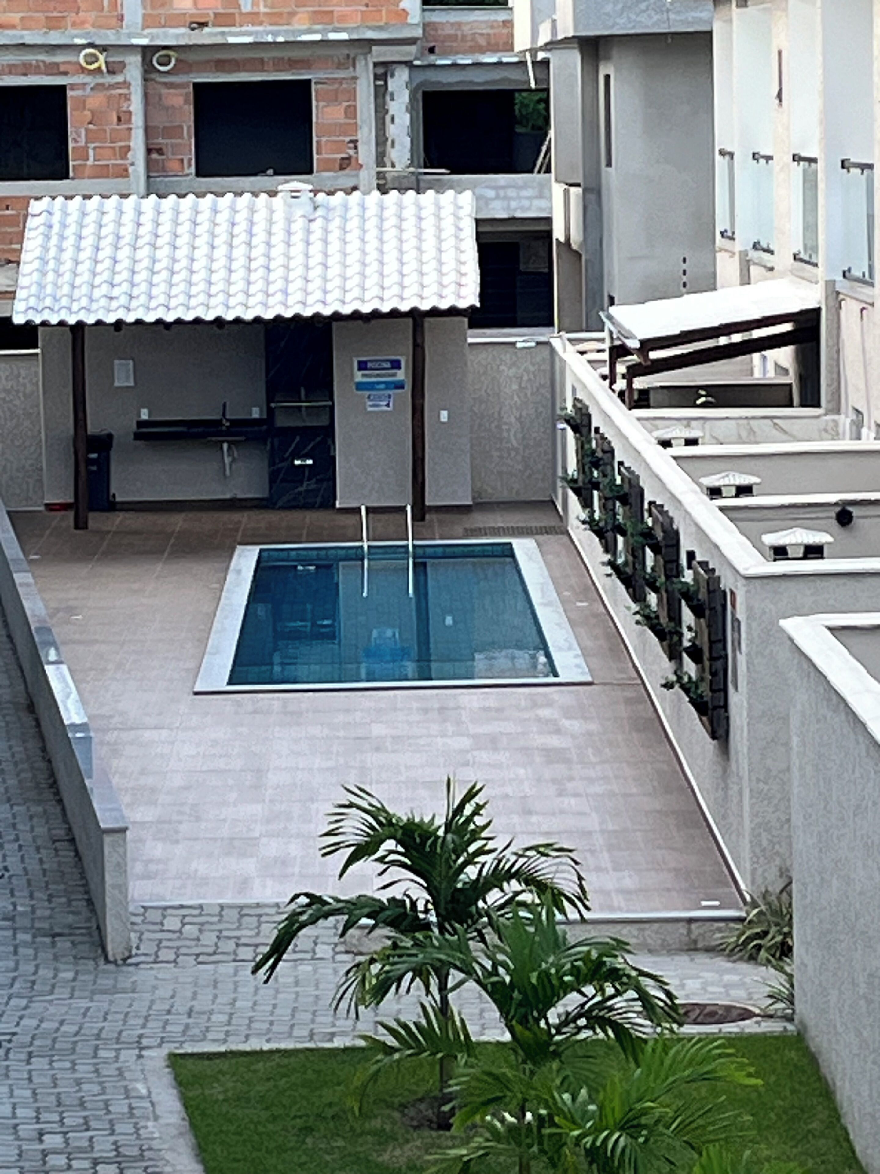 A rooftop swimming pool with a tiled roof, surrounded by a building with a brick facade and a sign indicating a public space.