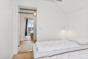 A bedroom with a bed, a door leading to a balcony, and a view of the outside. - Holiday apartment with sea view (Hadsund)