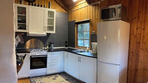 Una cocina compacta con gabinetes blancos, estufa, horno, microondas y refrigerador.