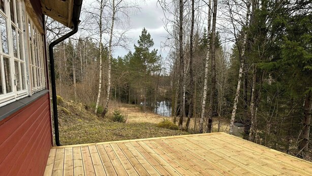 Una terraza de madera con vistas a un bosque y una masa de agua.