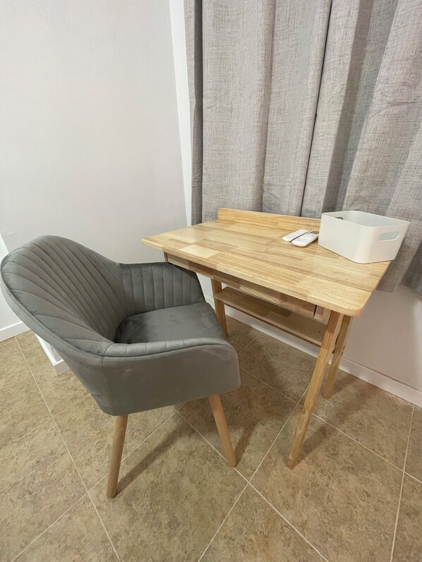 A small, modern room with a grey upholstered chair, a wooden table, and a white storage box. - Valentia Rooms - Baleares (València)