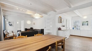 Una cocina moderna con armarios blancos, una mesa de comedor de madera y una lámpara colgante.