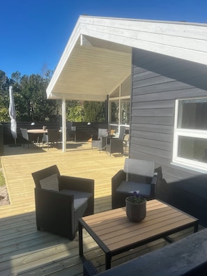 A covered outdoor patio with wicker furniture, a wooden table, and a pergola. - Holiday home with a covered terrace (Ålbæk)