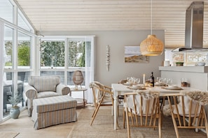 A dining area with a table set for four, surrounded by chairs with fur throw pillows. - Holiday home with a covered terrace (Ålbæk)