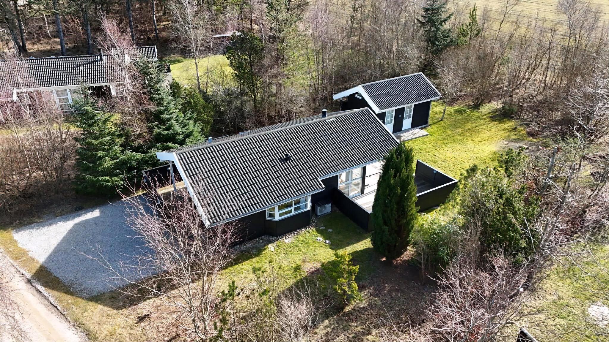 Een modern huis met twee verdiepingen en een schuin dak, gelegen in een bebost gebied.