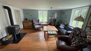 Ein gemütliches Wohnzimmer mit Kamin, Holzboden, einer Couch, einem Sessel und einem Tisch.