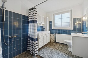 A bathroom with a shower, a toilet, a sink, and a window. - Relaxing holiday home near beach and harbour (Nexø)