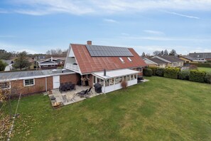 A house with a sloped roof, a covered patio, and a lawn. - Relaxing holiday home near beach and harbour (Nexø)
