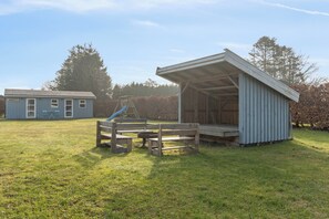 A small wooden structure with a porch and a play area with a slide. - Cosy holiday-house with annex close to the see (Hals)