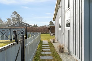 A pathway leading to a building with a white exterior and a gated entrance. - Cosy holiday-house with annex close to the see (Hals)