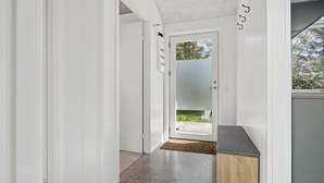A hallway with a door leading to an outdoor area, a wooden cabinet, and a textured floor. - Cozy little cottage, close to the Limfjord (Storvorde)