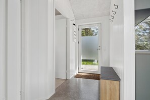 Un passadís amb una porta que condueix a zona exterior, un armari de fusta i un terraple de textura.