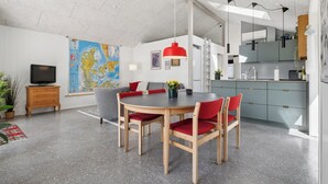 A modern living space with a dining table, chairs, a television, a map, and a kitchen area. - Cozy little cottage, close to the Limfjord (Storvorde)
