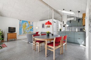 Un espace de vie moderne comprenant une table à manger, des chaises, un téléviseur, une carte et un coin cuisine.