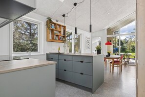 Una cocina moderna con una isla central, estanterías empotradas y un comedor con mesa y sillas.