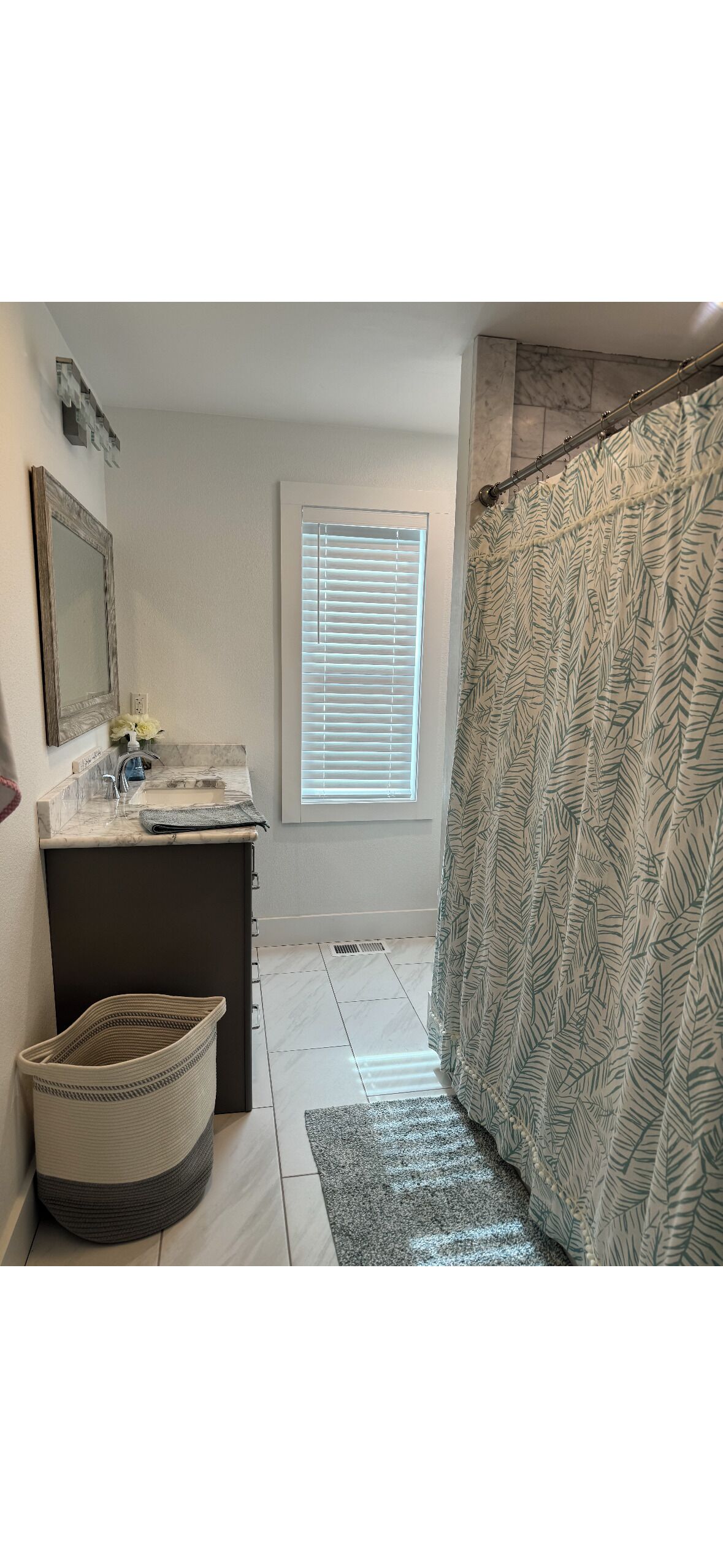 A bathroom with a sink, mirror, window, and shower curtain.