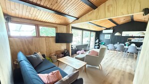 A cozy living area with a sofa, a coffee table, and a dining table with chairs. There is a television mounted on the wall and a window providing natural light. - Newly renovated holiday home by the fjord (Jægerspris)