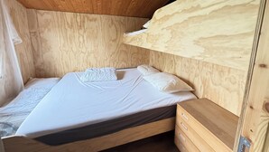 A wooden bunk bed with a mattress and pillows, a wooden nightstand with drawers, and a wooden ceiling with exposed beams. - Newly renovated holiday home by the fjord (Jægerspris)