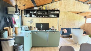 A compact kitchen with a sink, cabinets, and a countertop. There is a dining area with a table and chairs. - Newly renovated holiday home by the fjord (Jægerspris)