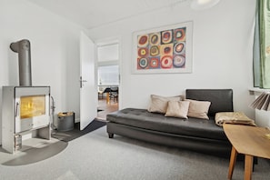 A modern living room with a sofa, a fireplace, and a colorful abstract painting. - Centrally located townhouse with port/seaviews. (Allinge)