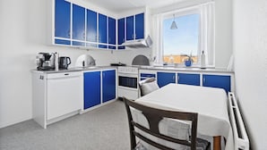Une cuisine avec des meubles bleus, un plan de travail blanc, une cuisinière, un évier et une fenêtre donnant sur un beau paysage.
