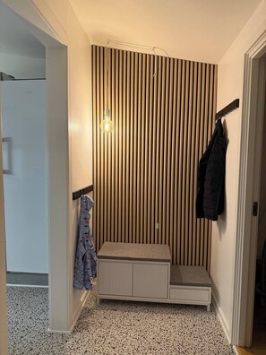 A small room with a bench, a coat rack, and a wall-mounted light fixture. - Family-friendly cottage near forest and castle (Hillerød)